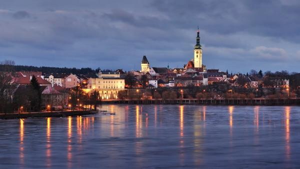 Táborer Altstadt in der Dämmerung; im Vordergrund Wasser, auf dem sich die Lichter der Stadt spiegeln
