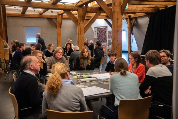 mehrere Personen an einem Tisch basteln eine Collage