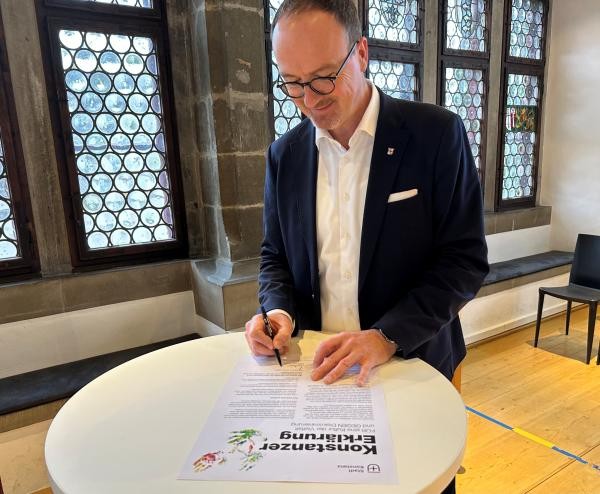 Mann an Stehtisch unterschrift ein Blatt Papier