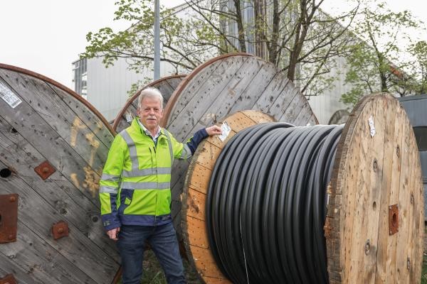 Ein Mann mit gelber Weste steht vor einer Kabeltrommel