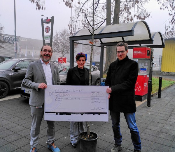Übergabe des Spendenschecks und eines Apfelbaumes an Stadtwerke-Vertreter vor der Biogas-Tankstelle 