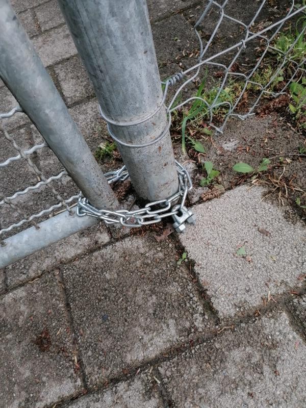 Türe in einem Zaun mit einem Vorhängeschloss daran