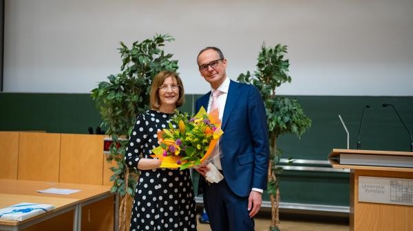 Frau und Mann im Innenbereich. Sie hält einen Blumenstrauß.