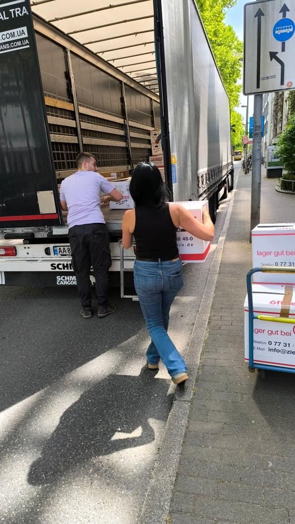 Zwei Menschen verladen Umzugskisten in einen LKW