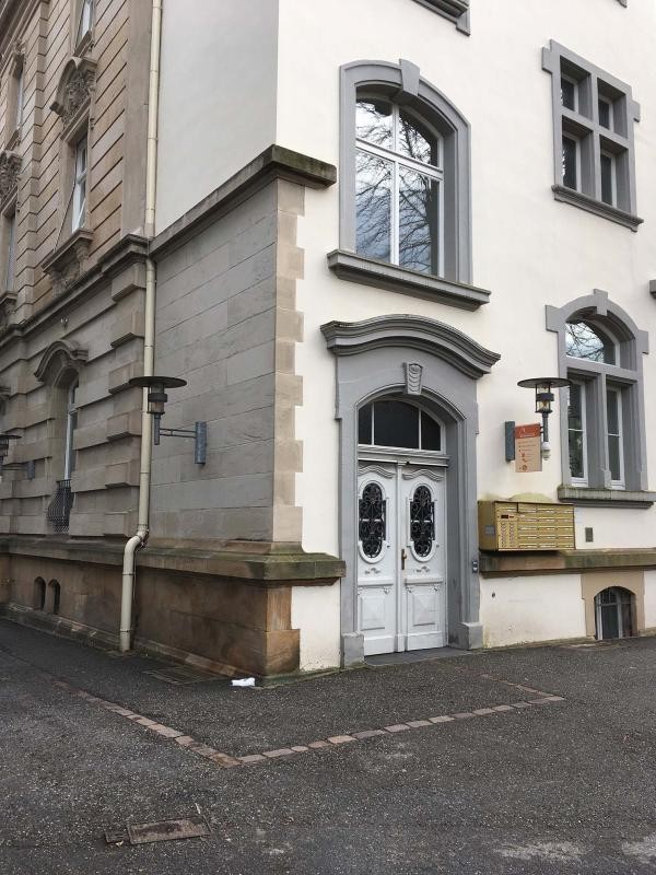 Auf dem Bild zu sehen ist eine Hausecke, sowie eine große weiße Eingangstüre und mehrere Fenster, die ebenfalls weiß sind.