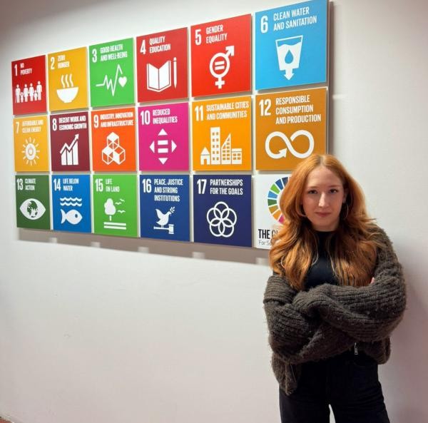 Politikwissenschaftlerin Anastasiia Khitrova steht an einer Themenwand.