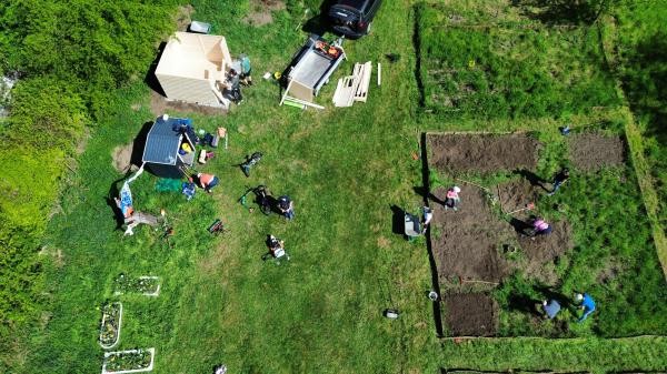 Eine grüne Rasenfläche von oben. Darauf sind Beete abgesteckt, die als braune Rechtecke mit Bepflanzung den Rasen unterteilen.