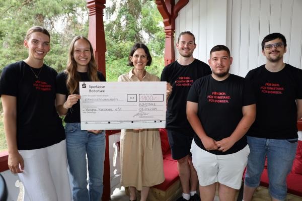 Fünf Auszubildende übergeben einen Spendenscheck an die Vertreterin der Kinderhospizarbeit.