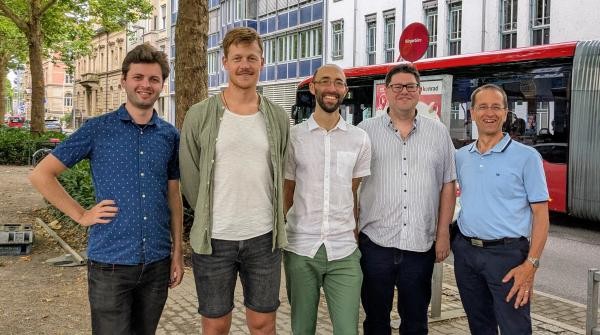 Fünf Männer stehen nebeneinander auf der Laube in Konstanz. Im Hintergrund ist ein roter Linienbus der Stadtwerke Konstanz zu sehen. Von links nach rechts: Jakob Everling (Fußverkehrsbeauftragter), Christopher Hainsch (Verkehrsplaner), Gregor Gaffga (Radverkehrsbeauftragter), Sebastian Nadj (Stv. Abteilungsleiter) und Stephan Fischer (Abteilungsleiter).