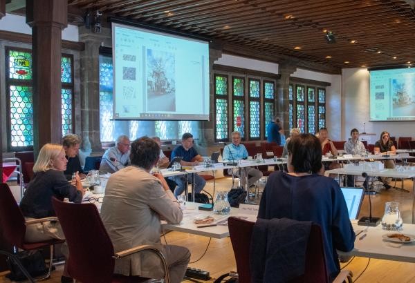 Auf dem Bild zu sehen sind mehrere Menschen, die in der Gestaltungsbeiratssitzung im Ratssaal des Konstanzer Rathauses sitzen und diskutieren.