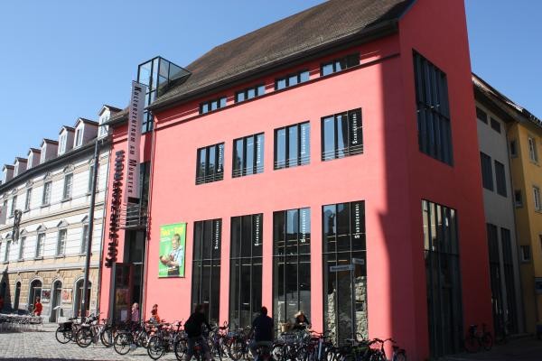 Bild von einem roten Gebäude, dahinter blauer Himmel