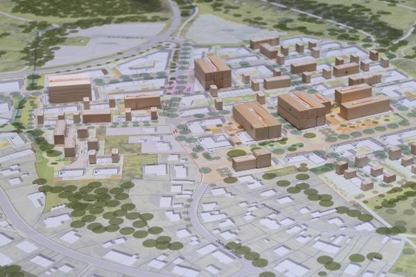 Bild von einem Stadtplan mit architektonischen Zeichnungen von Häusern, Straßen und Bäumen  mit Holzklötzen darauf, die Häuser immitieren
