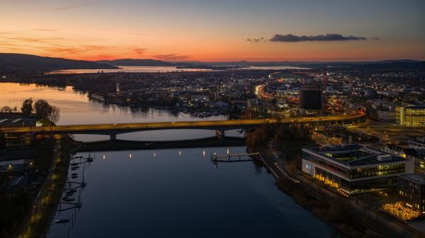 Abendstimmung über Konstanz mit Blick auf die sanft beleuchtete Europabrücke rheinabwärts. Der Himmel glüht in orange und blau
