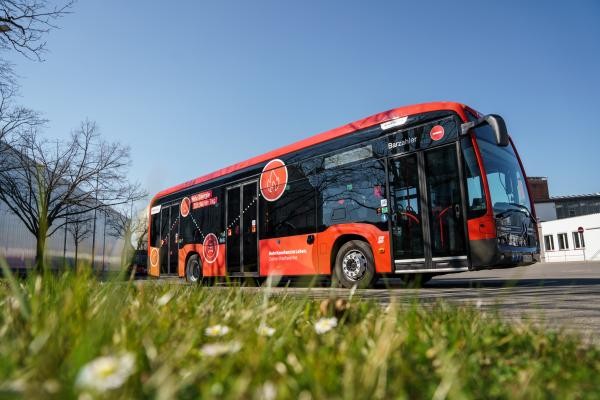 Ein roter Bus mit einer grünen Wiese im Vordergrund