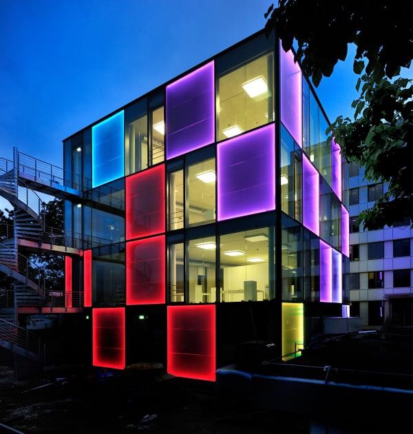 Ein bunt beleuchtetes quadratisches Gebäude bei Nacht