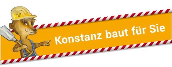 Banner mit dem Text „Konstanz baut für Sie" auf orangefarbenem Hintergrund mit rot-weißem Absperrband. Links steht eine Zeichenfigur – ein Maulwurf mit gelbem Schutzhelm und Schaufel.