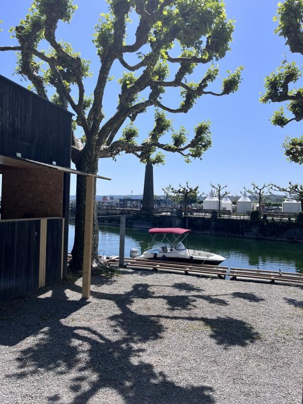 Blick auf den Gondelehafen in Konstanz: Unter einem großen Baum stehen neben einem Steg mehrere weiße Zelte, im Hintergrund ist das Wasser mit geparkten Booten zu sehen.