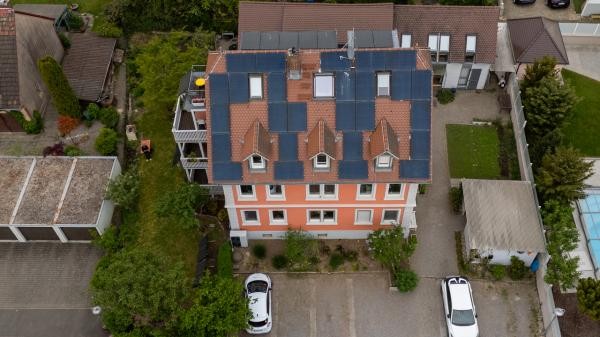 Blick von oben auf ein Mehrparteienhaus mit Photovoltaik auf dem Dach
