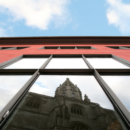 Blick von unten in ein Fenser des Kulturzentrums, auf dem sich das Konstanzer Münster spiegelt.