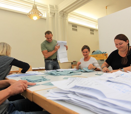 Eine Gruppe WahlhelferInnen zählt Stimmzettel aus.