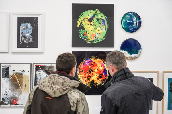 Bild der Mitgliederausstellung des Kunsvereins: zwei Besucher sind von hinten vor den ausgestellten Werken zu sehen.