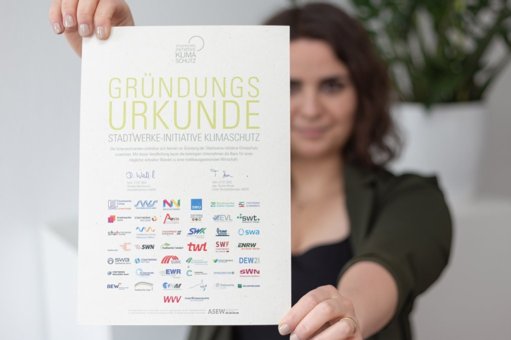 Eine Frau hält die Gründungsurkunde der Stadtwerke-Initiative Klimaschutz ins Bild