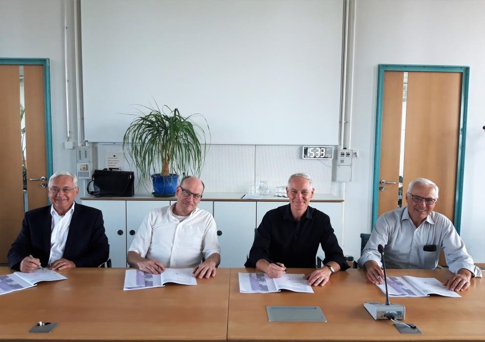Vier Herren am Tisch, die einen Vertrag unterzeichnen