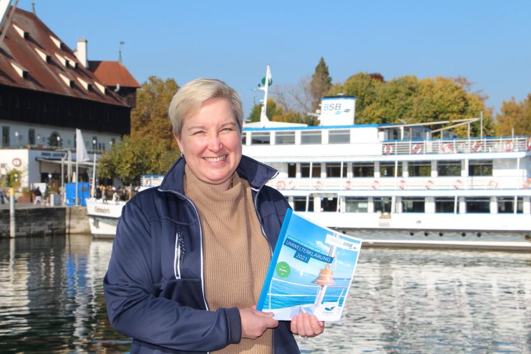 Charlotta Skoglund vor dem Konstanzer Hafen, in ihren Händen hält sie die neue Umwelterklärung