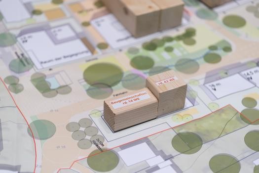 Kleine Holzblöcke auf einem Plan mit architektonischen Abbildungen von Häusern und Bäumen