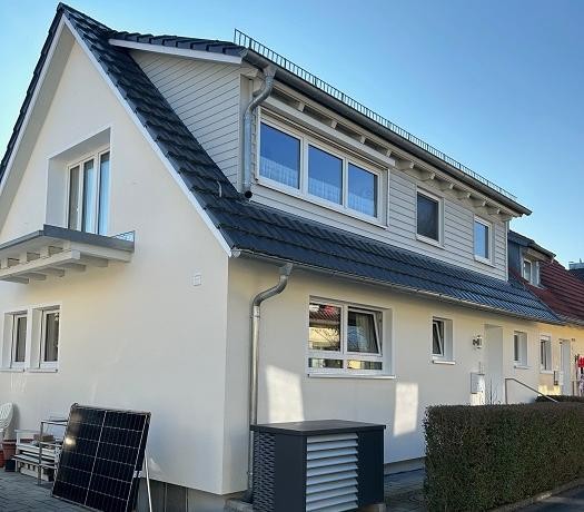 Foto einer Doppelhaushälfte mit Wärmepumpe davor