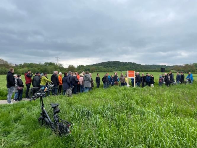 Große Gruppe Menschen, die einen Weg zwischen zwei Wiesen entlanggehen