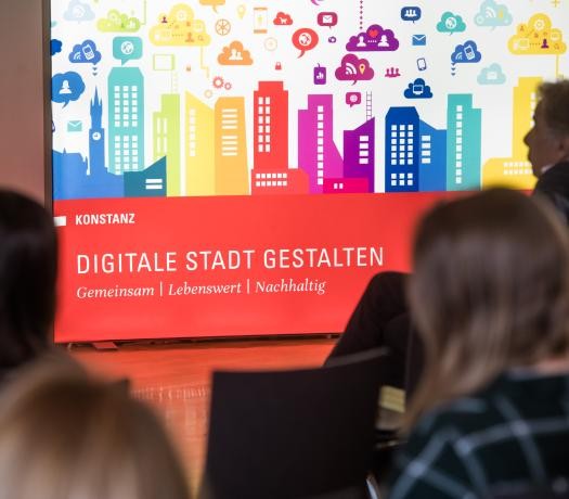 Digitale Stadt gestalten Plakat mit ZuhörerInnen im Vordergrund