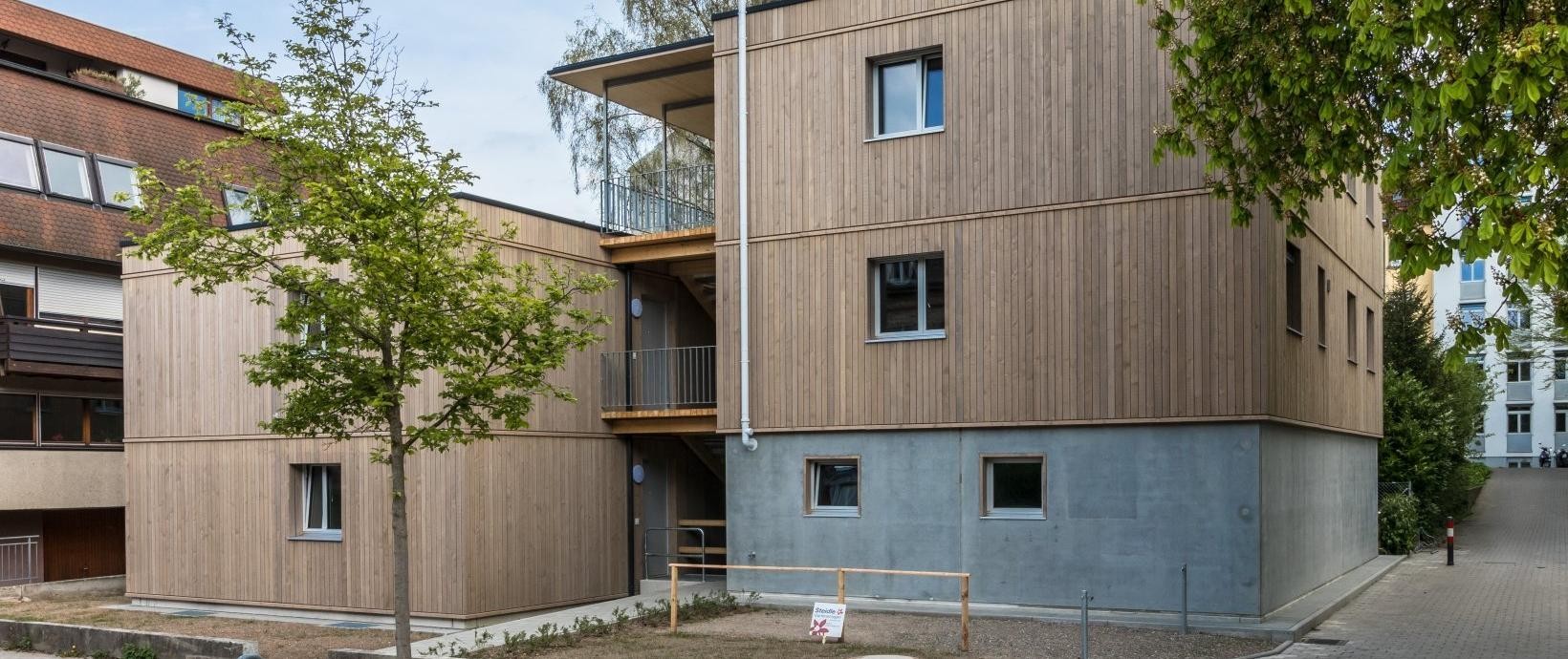 Flachdach-Haus mit Holzfassade und Bäumen davor