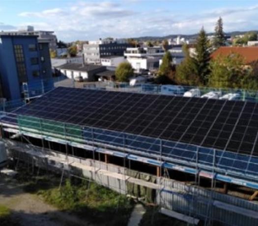 Blick auf das Dach einer Lagerhalle, das mit Photovoltaik-Modulen belegt ist