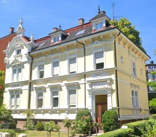 Gründerzeitvilla mit hellgelber Fassade und weißen Stuck-Elementen