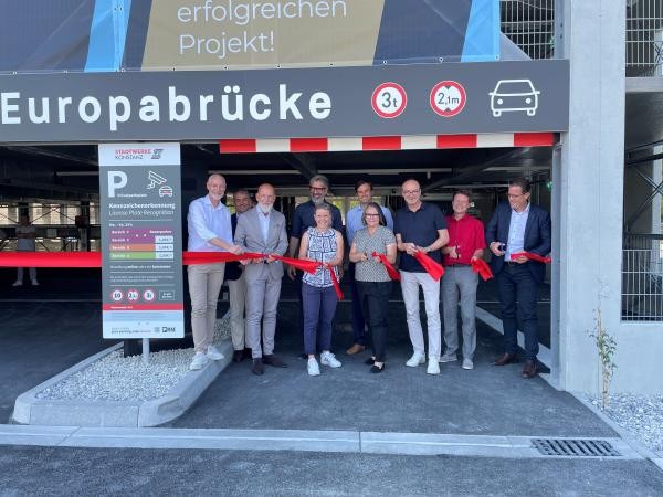 Mehrere Personen schneiden das rote Band an der Einfahrt zum neuen Parkhaus durch. 