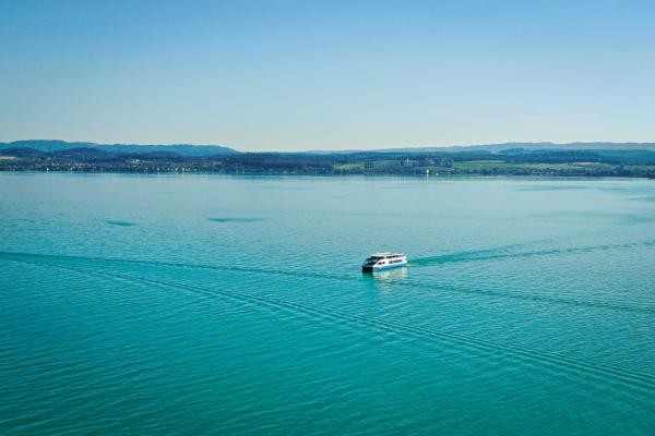 Ein Schiff fährt über den blauen Bodensee, Aufnahme von oben.