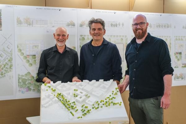Copyright Stadt Konstanz Drei Männer stehen vor einer Wand an der Architekturpläne hängen, die Männer halten ein Architekturmodell nach oben