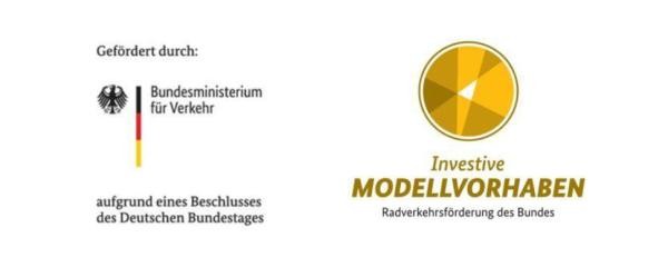Das Bild zeigt zwei Logos nebeneinander. Links ist das Logo des Bundesministeriums für Verkehr mit Bundesadler und Deutschlandfarben, begleitet vom Text „Gefördert durch… aufgrund eines Beschlusses des Deutschen Bundestages“. Rechts befindet sich ein goldenes Kreislogo mit der Aufschrift „Investive Modellvorhaben – Radverkehrsförderung des Bundes“.