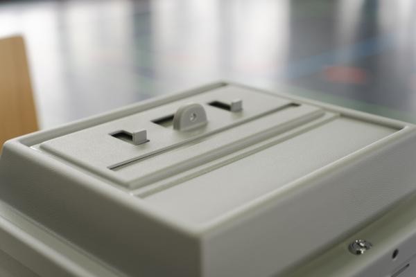 zu sehen ist eine graue Wahlurne aus Kunststoff in der Nahaufnahme