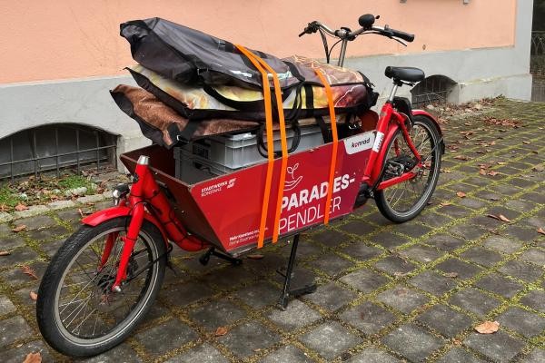 Ein mit Taschen und einer Kiste bepacktes rotes Lastenrad