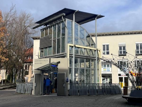 Ein Eingang zu einer Tiefgarage mit Glas überdacht.