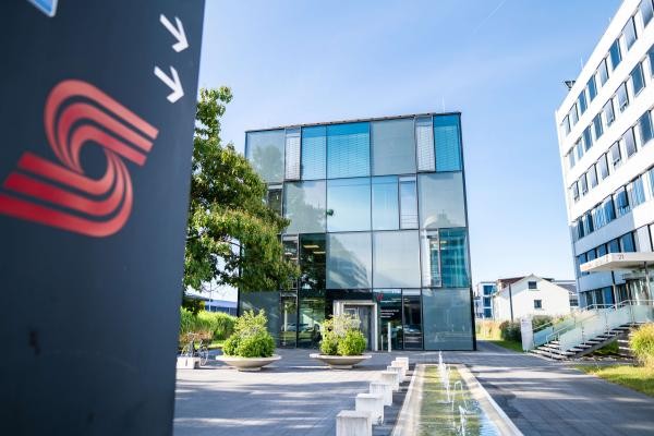 Ein Gebäude mit Glasfront und das Logo der Stadtwerke auf einem Schild im Vordergrund