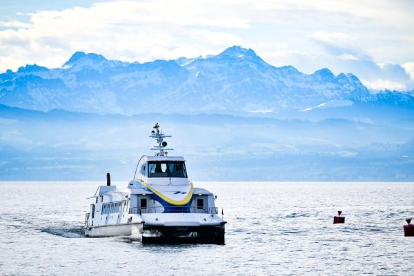Katamaran im Winter auf dem See. Im Hintergrund schneebedeckte Berge