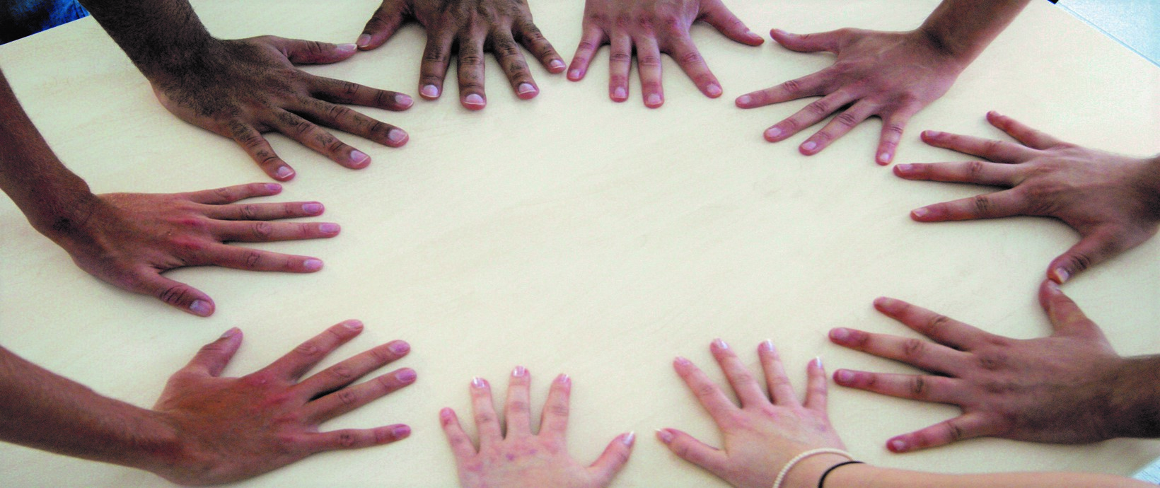 Menschen bilden auf einem Tisch mit ihren Händen einen Kreis