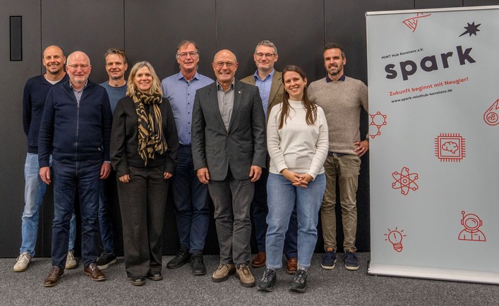 Personen stehend neben einem Rollup mit Schriftzug spark