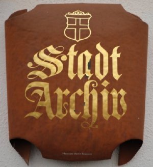 Ein rostbraunes Schild trägt den goldenen Schriftzug"Stadtarchiv".