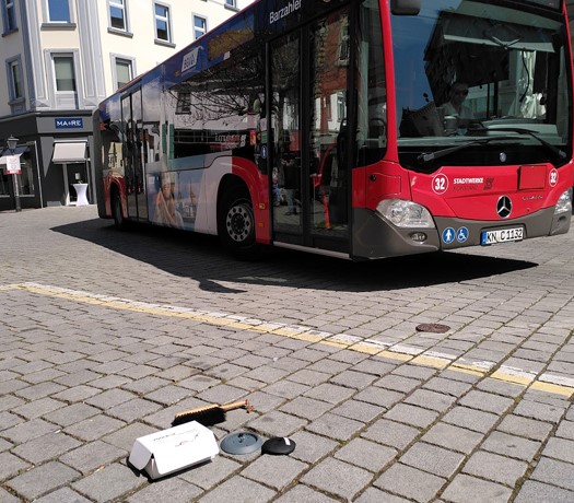 Parkraumsensor am Boden vor dem Anbringen, im Hintergrund ein roter Bus