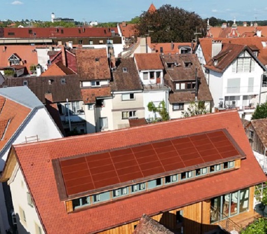 Foto eines Gebäudes mit roter Photovoltaikanlage auf dem Dach