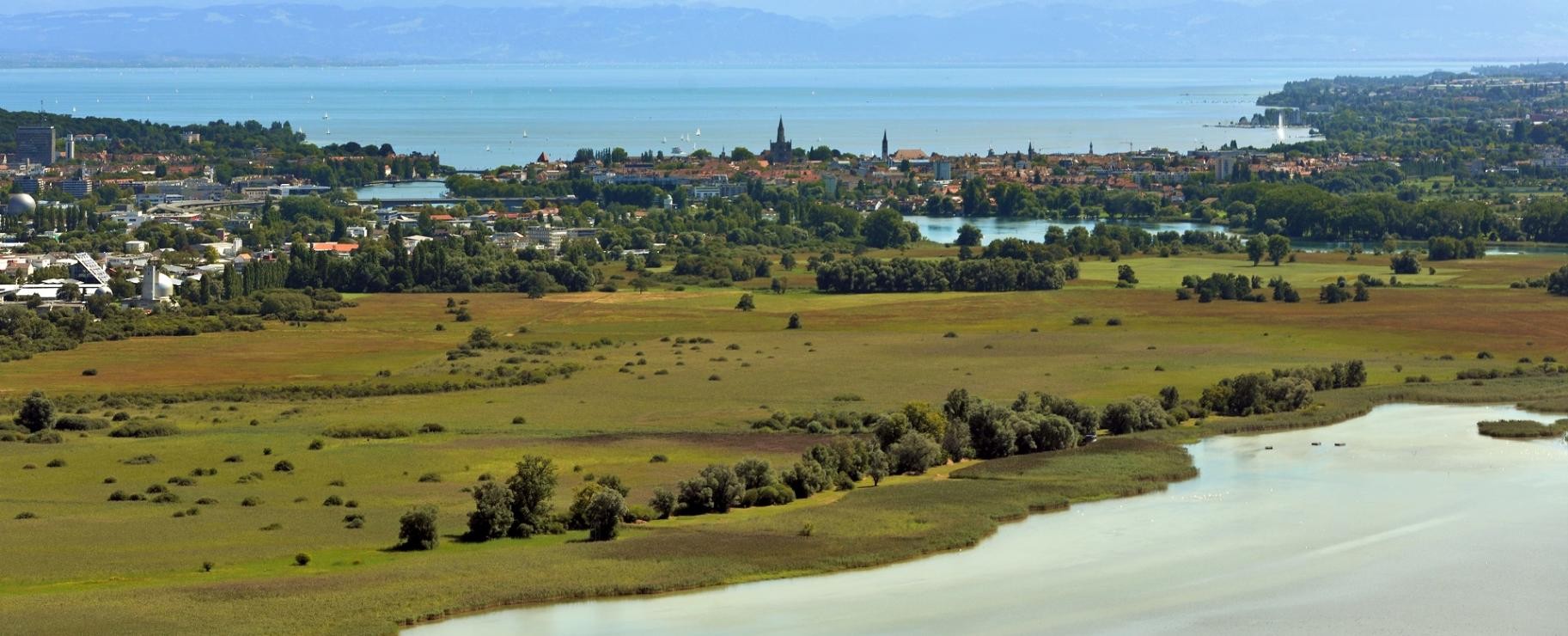 Konstanz aus der Ferne, im Hintergrund der Bodensee und Berge